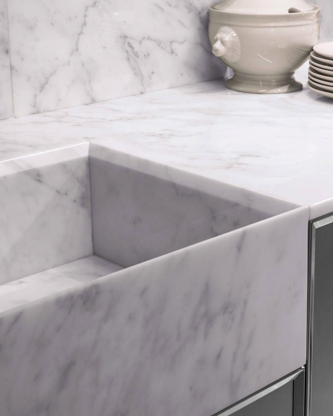 Bianco Carrara marble benchtop with an integrated sink, matching splashback and white crockery