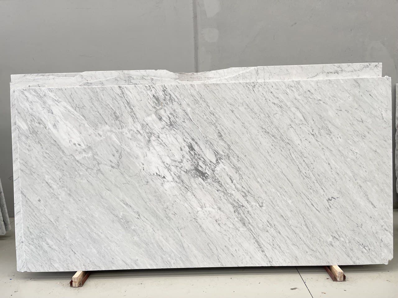 White and grey Bianco Carrara marble slabs displayed on timber supports